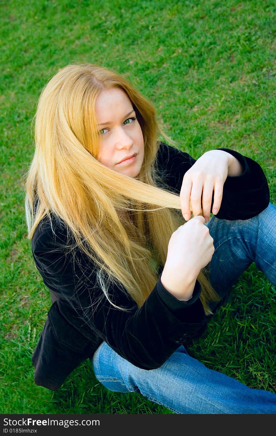 Young attractive woman sitting on green grass