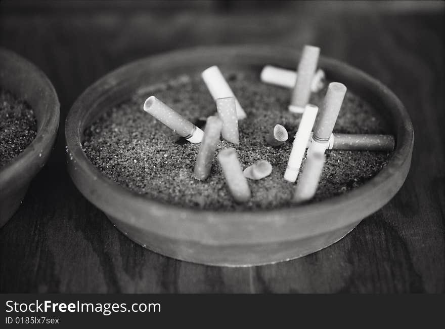 Black and white image of several cigarettes in an ashtray.