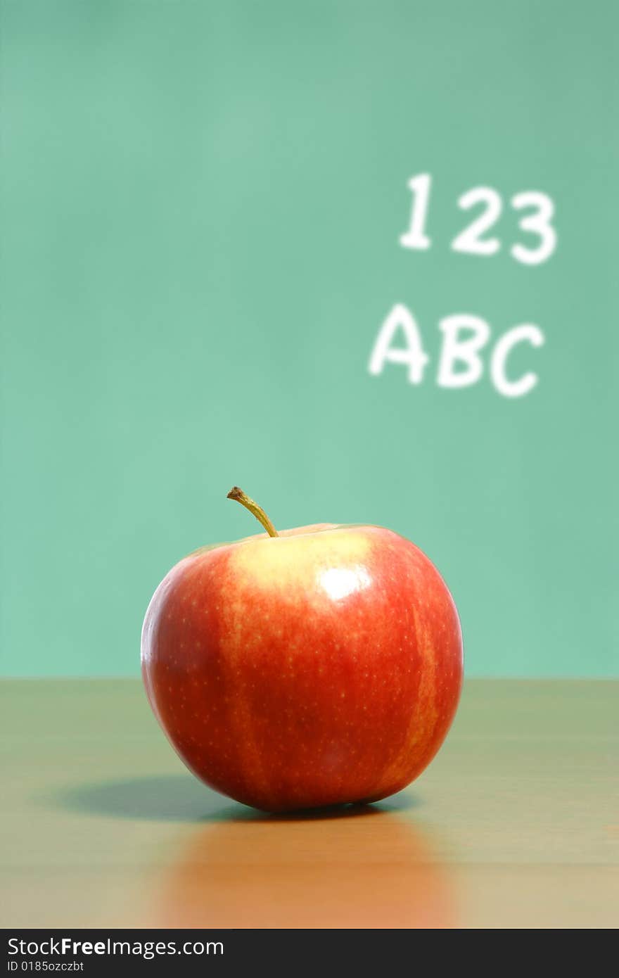 An apple on a desk in a classroom with abc 123