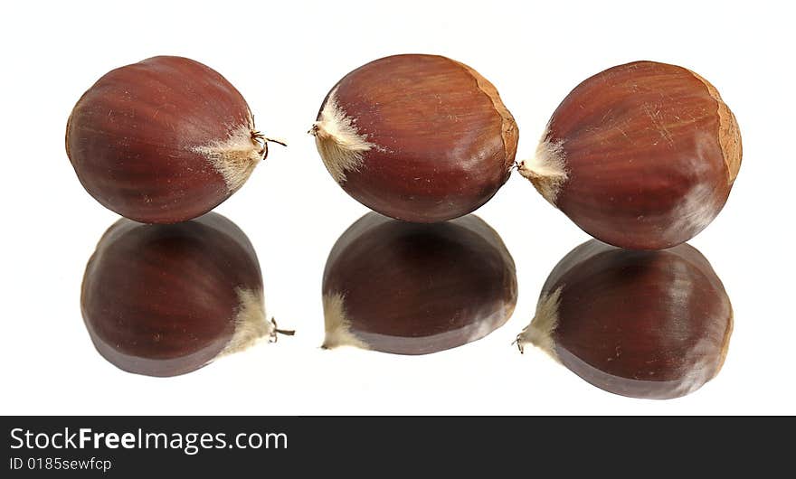 Three chestnuts on a reflective surface