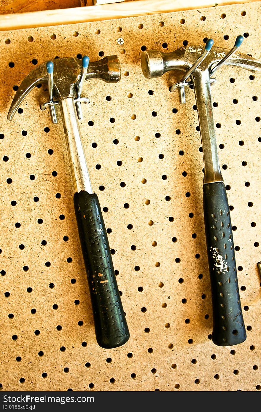 Two hammers hanging from pegboard in storage shed. Two hammers hanging from pegboard in storage shed