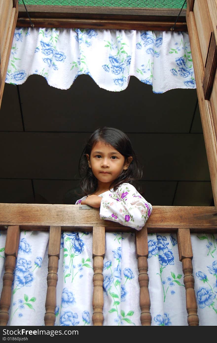 A Malaysian girl wearing malay traditional clothe standing by window in a traditional malay house.
