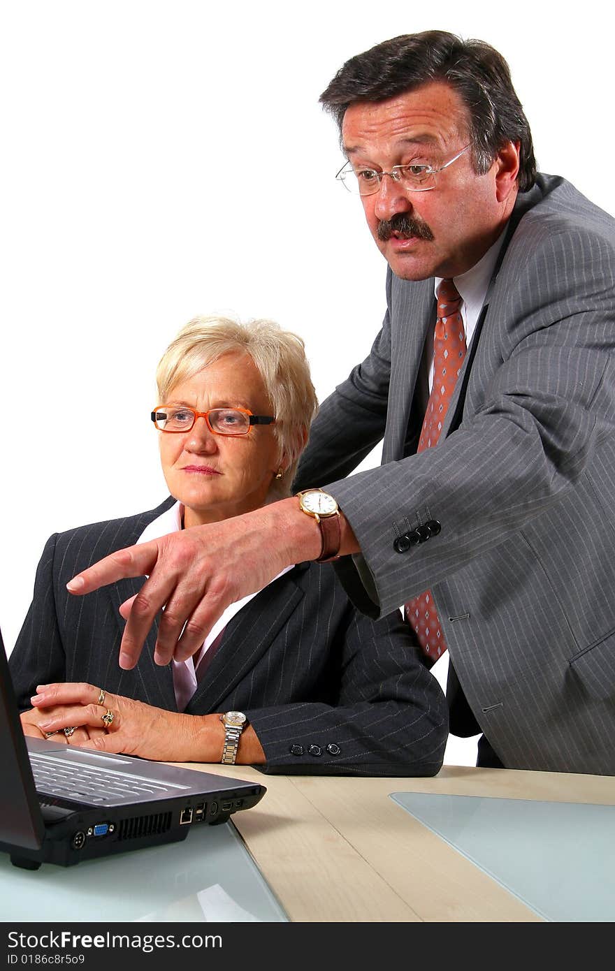 A business woman and a man in front of a laptop on a desk. The man explains something to the woman. Isolated over white. A business woman and a man in front of a laptop on a desk. The man explains something to the woman. Isolated over white.