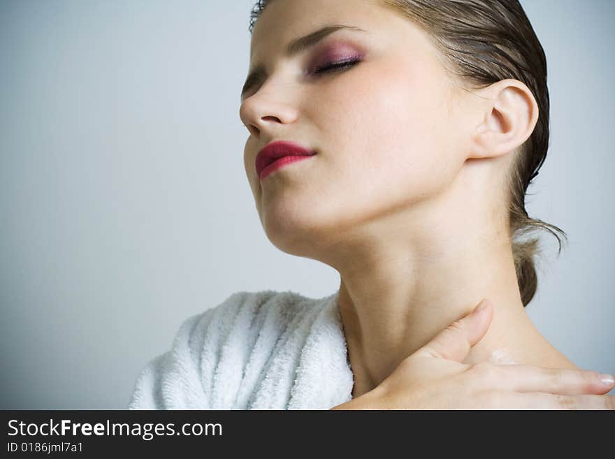 Beautiful woman in bathrobe massaging her skin. Beautiful woman in bathrobe massaging her skin.