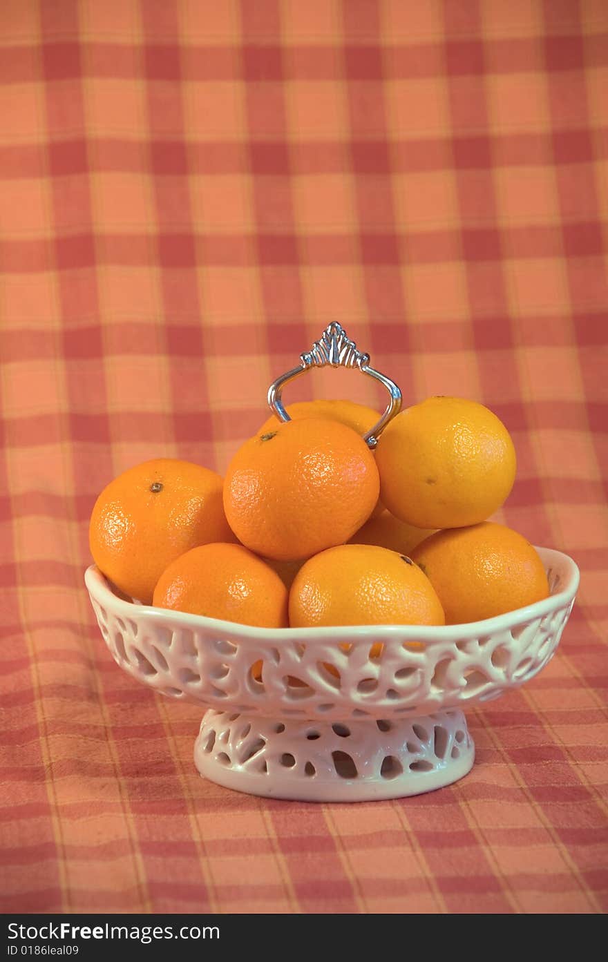 Luxe white Bowl filled with mandarin fruit on an orange checkered background. Luxe white Bowl filled with mandarin fruit on an orange checkered background