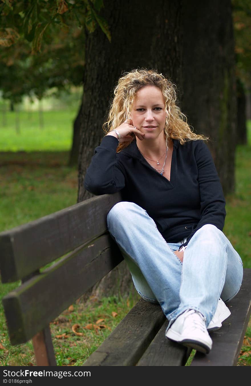 Girl sitting on bench in park. Girl sitting on bench in park