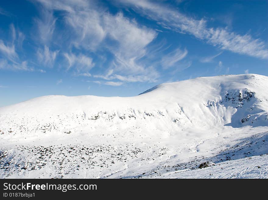 Winter sunny day over mountain slopes covered by snow