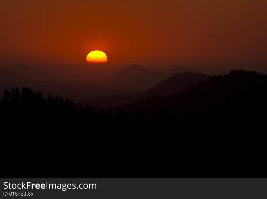 The sun sets behind layers of mountains in the Sierra Mountains of California. The sun sets behind layers of mountains in the Sierra Mountains of California.