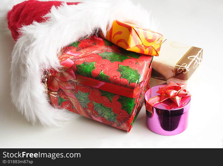 Santa's red hat and small gifts in white background. Santa's red hat and small gifts in white background