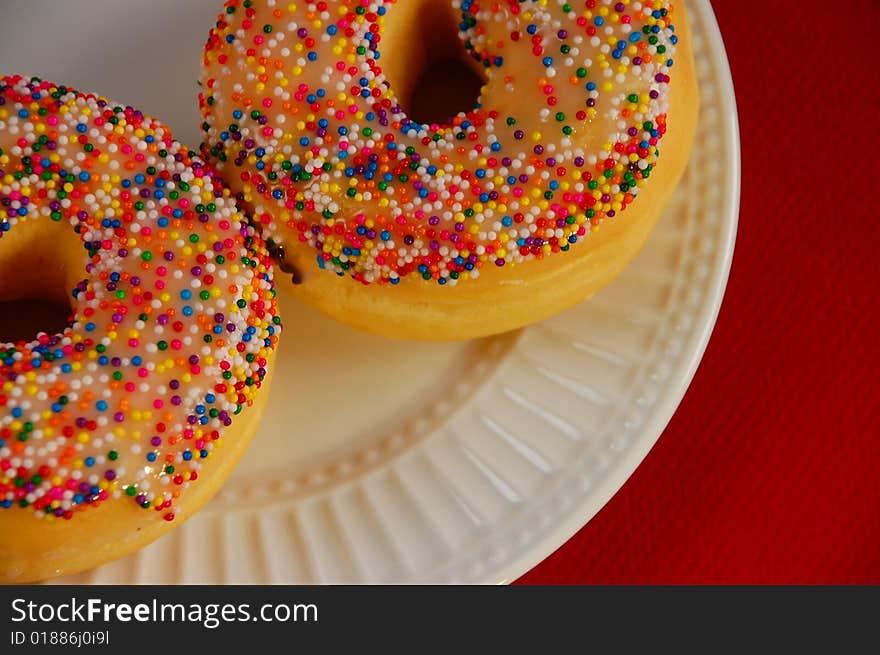 Sprinkle donuts on white plate against white background