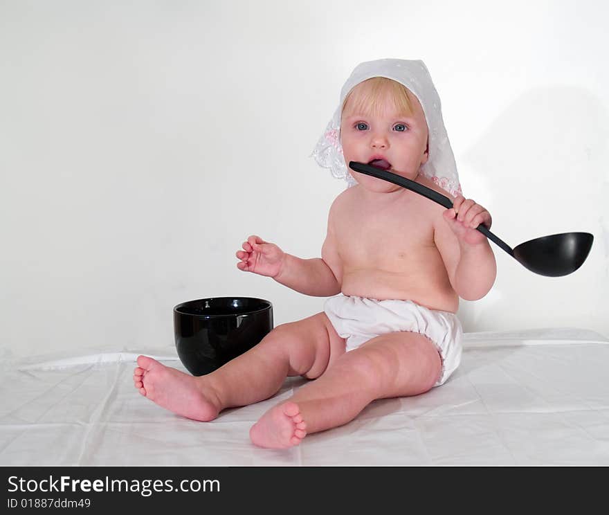 Child in hat plays ladle. Child in hat plays ladle