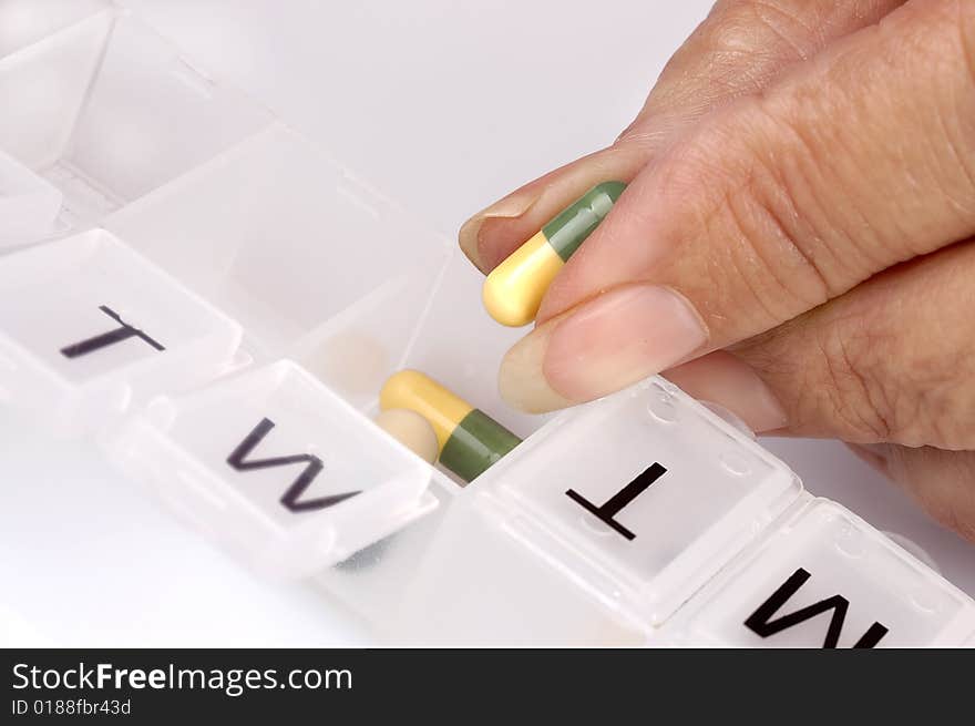 A Hand Sorting Capsules To A Pill Dispenser