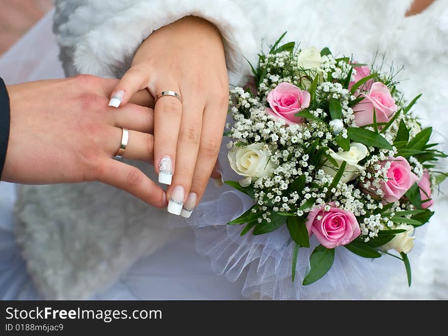 Newly-weds hold a wedding bouquet in the hands