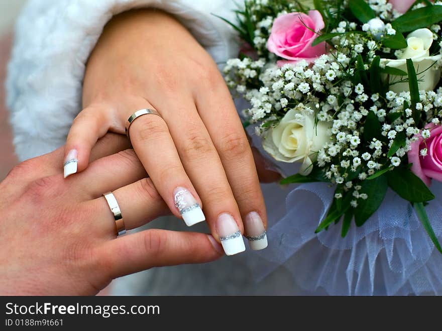 Newly-weds hold a wedding bouquet in the hands