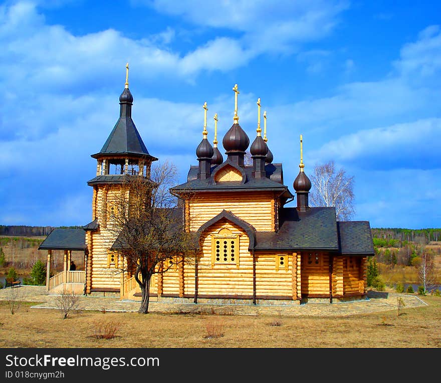 Rural orthodox church from logs on a background of the blue sky and clouds. Rural orthodox church from logs on a background of the blue sky and clouds