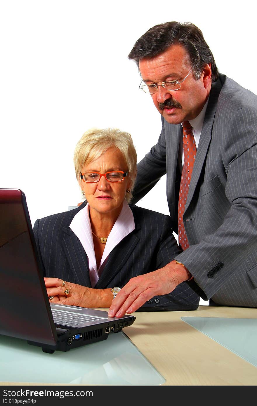 A business woman and a man in front of a laptop on a desk. The man explains something to the woman. Isolated over white. A business woman and a man in front of a laptop on a desk. The man explains something to the woman. Isolated over white.