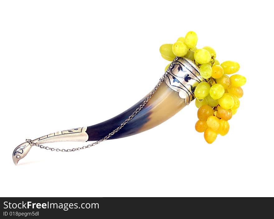 Drinking horn and grapes isolated on white background