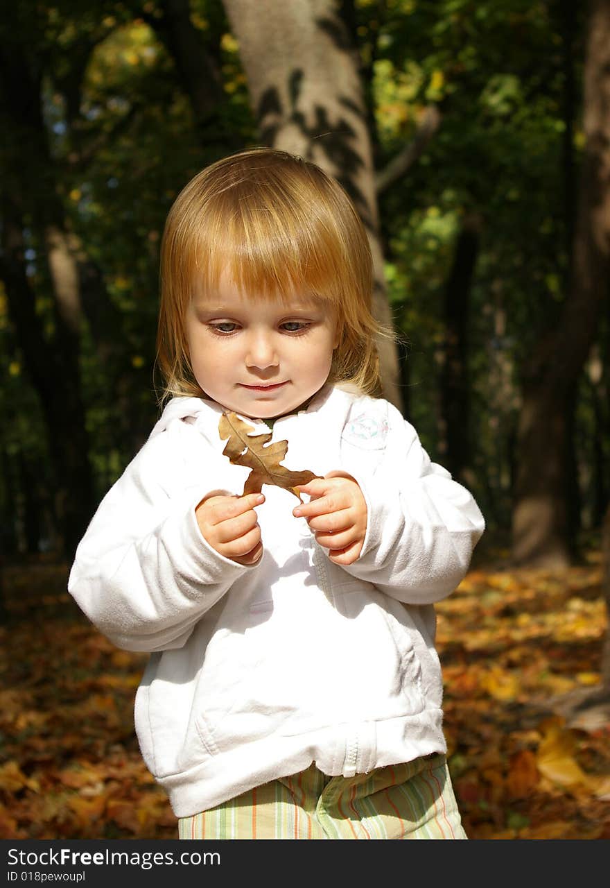 Autumn portrait of cute little girl with oak leaf