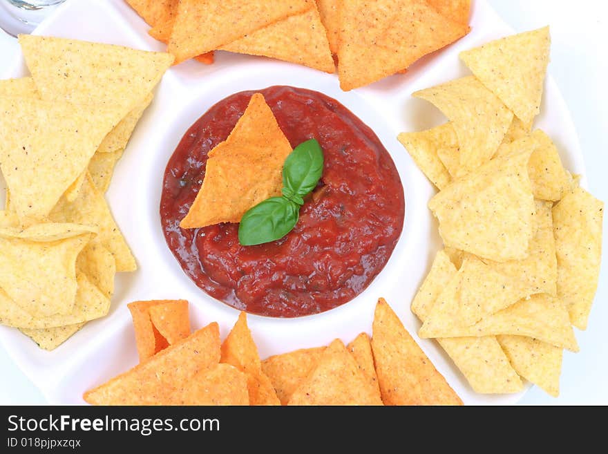 Nachos and salsa dip with basil , in a bowl