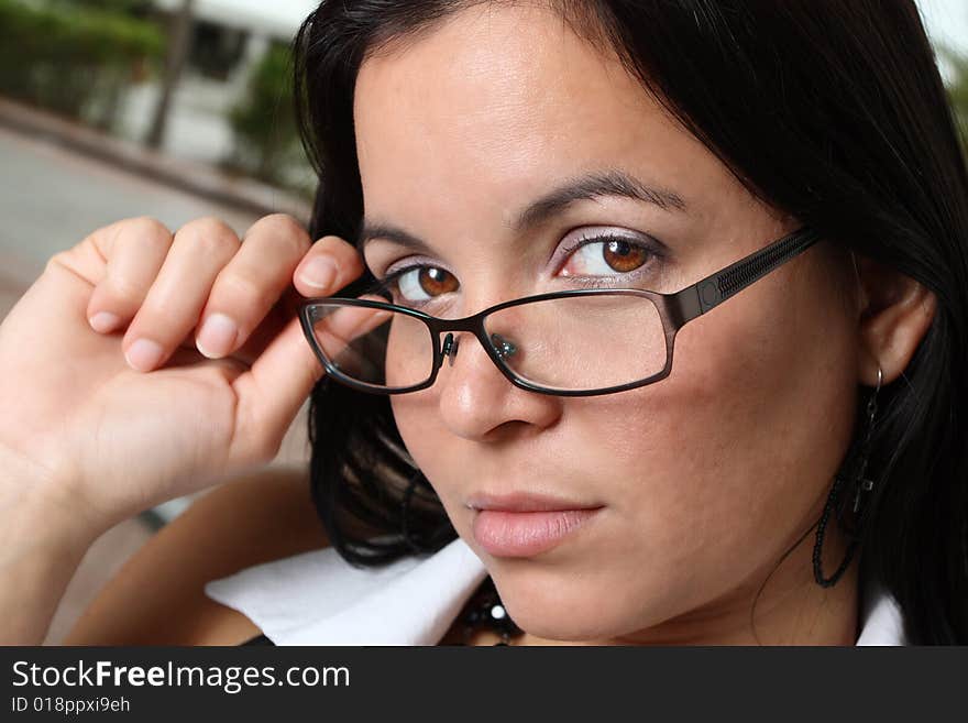 Young woman pulling down her glasses to reveal her beautiful brown eyes. Young woman pulling down her glasses to reveal her beautiful brown eyes