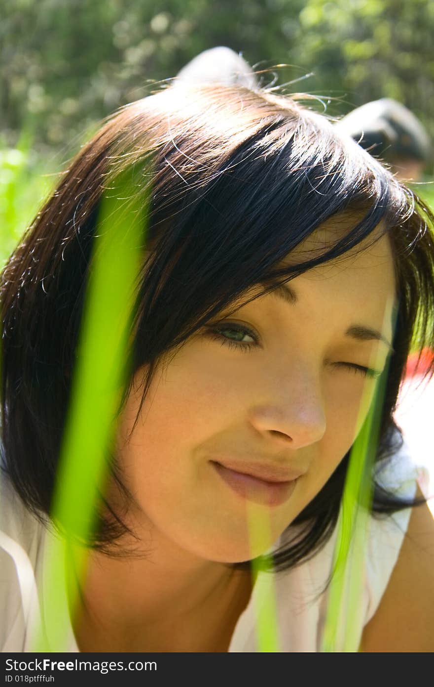 Beautiful young girl on a field among fresh green grass