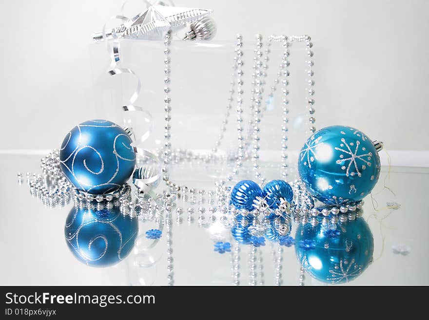 A lovely blue baubles on a mirror  surface with ribbons and beads. A lovely blue baubles on a mirror  surface with ribbons and beads.