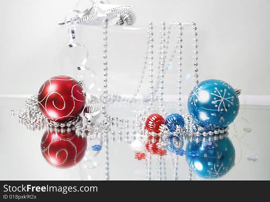 A lovely blue and red baubles on a mirror  surface with ribbons and beads. A lovely blue and red baubles on a mirror  surface with ribbons and beads.