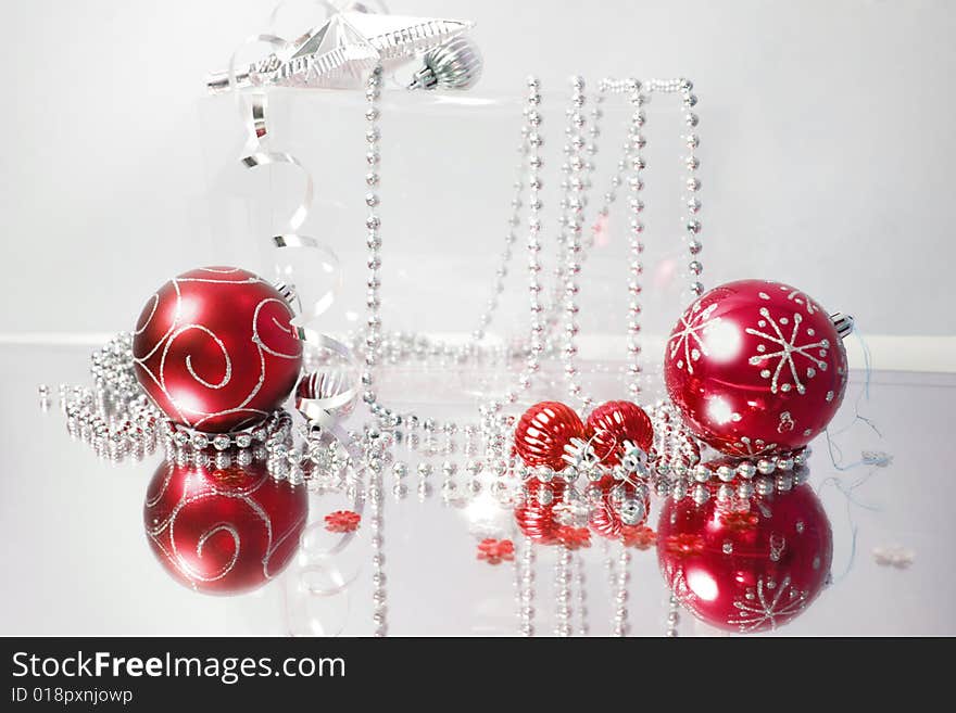 A lovely red baubles on a mirror  surface with ribbons and beads. A lovely red baubles on a mirror  surface with ribbons and beads.