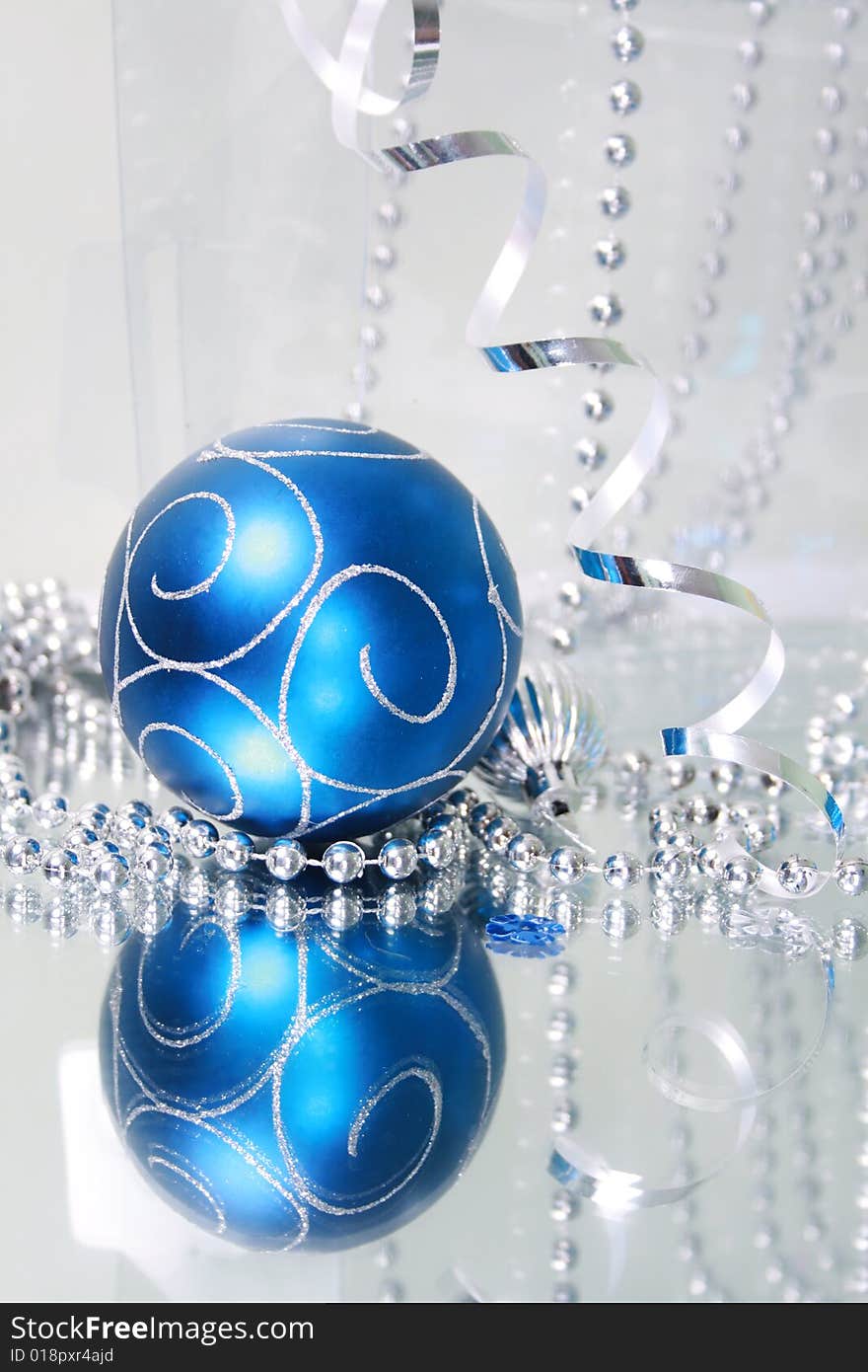 A lovely blue baubles on a mirror  surface with ribbons and beads. A lovely blue baubles on a mirror  surface with ribbons and beads.