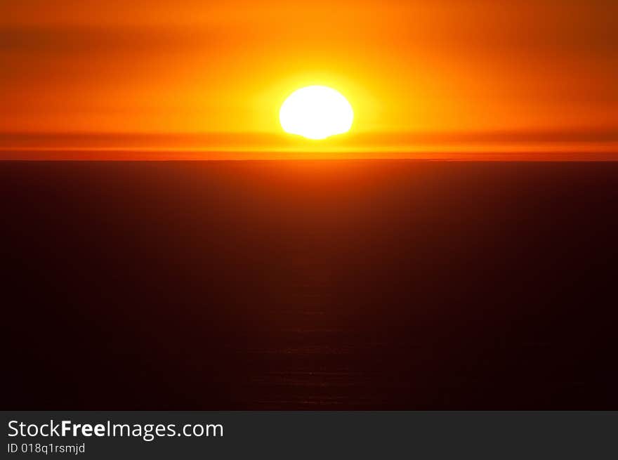 The sun setting over the Pacific Ocean gives a warm, orange glow to the sky. The sun setting over the Pacific Ocean gives a warm, orange glow to the sky.