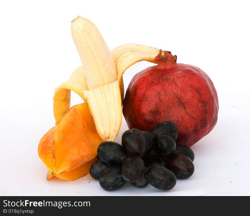 Banana, pomegranate, carambola, and grapes isolated on white background