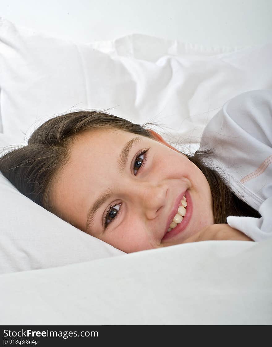 Young girl lying in bed smiling at camera