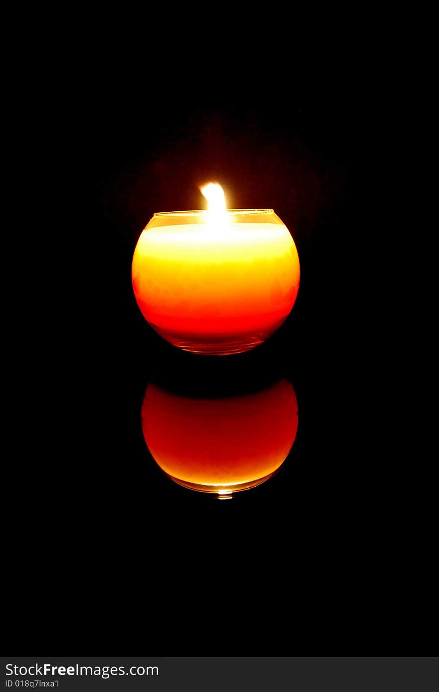 A candle with black background reflected