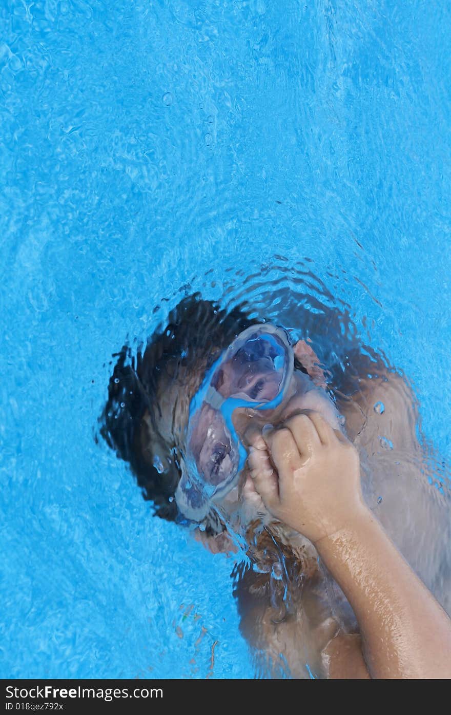 A young boy in pool with goggles on. A young boy in pool with goggles on