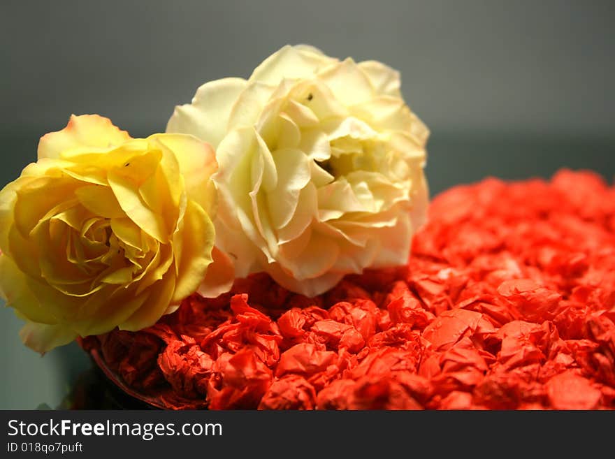 Two yellow roses on a black stage against a red paper heart on background. Two yellow roses on a black stage against a red paper heart on background