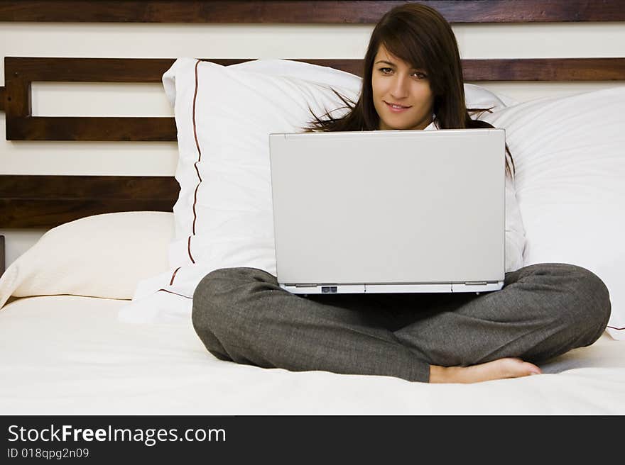 Young smiling businesswoman using laptop in bed. Young smiling businesswoman using laptop in bed