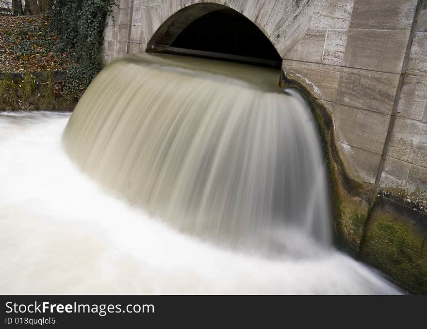 Small waterfall under a bridge in the English Garden, Munich, Germany.