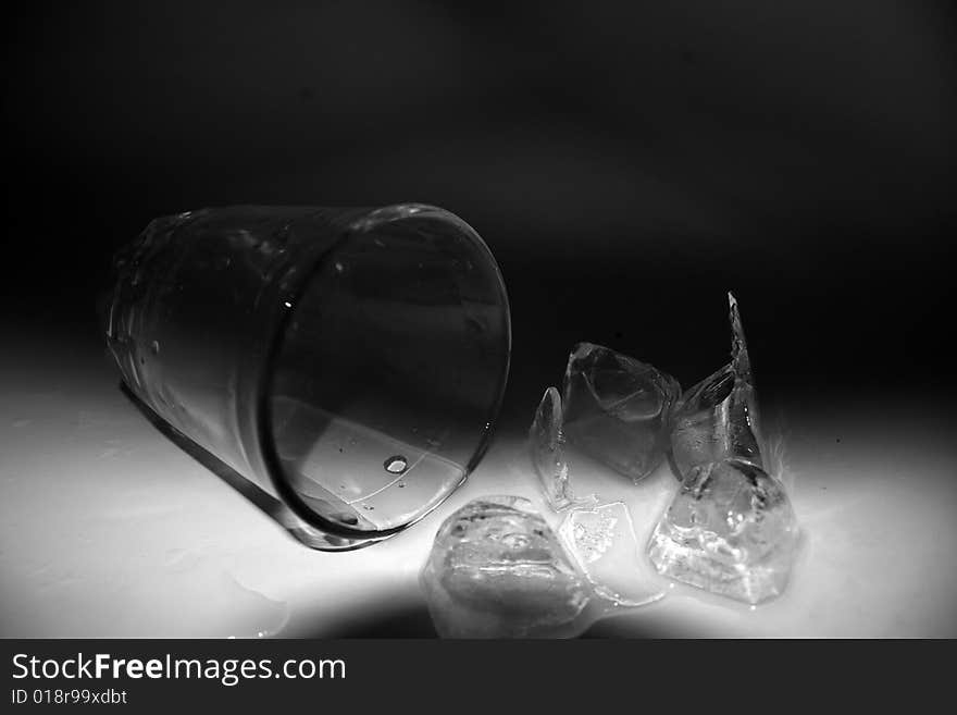 The fallen thick glass tumbler, the poured out ice, water. The fallen thick glass tumbler, the poured out ice, water