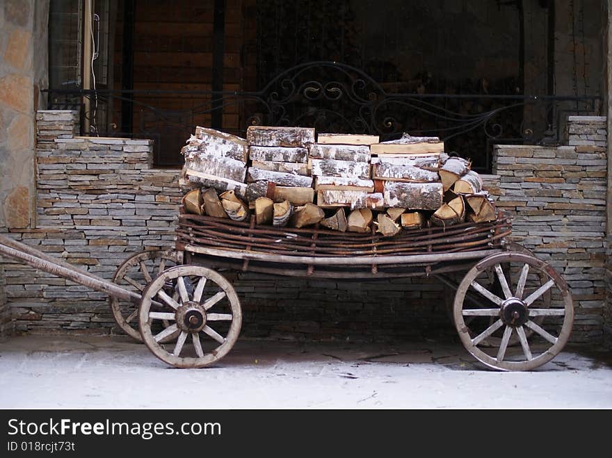 Old cart with wood with stone wall at background