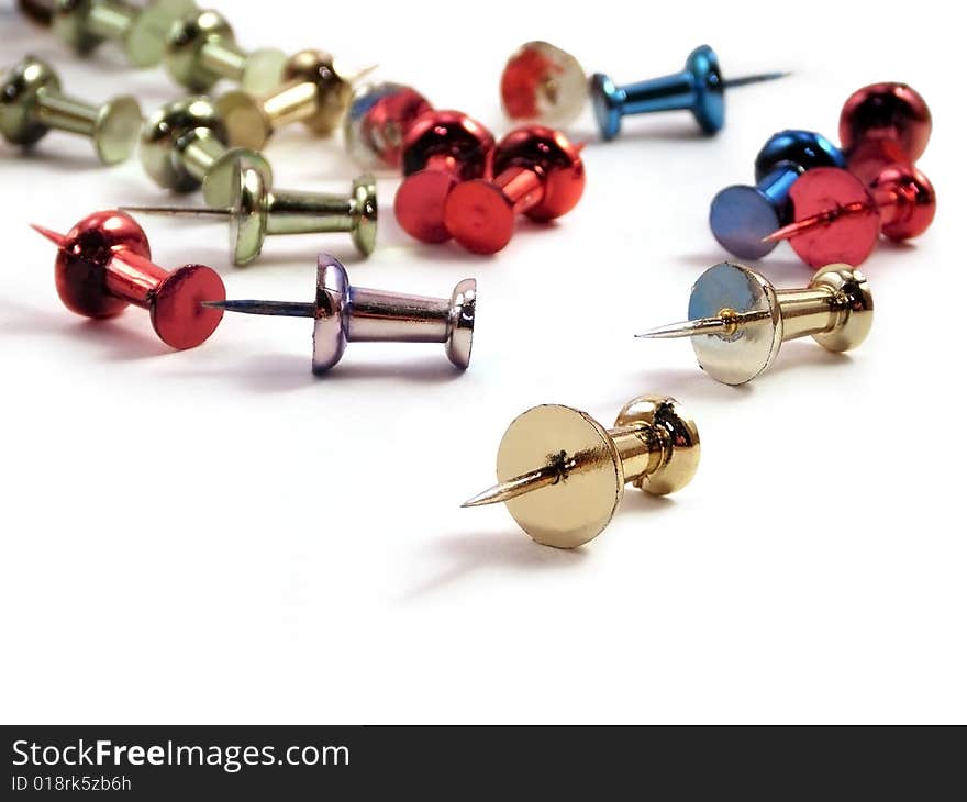 Colored metallic thumb tacks against a white background.