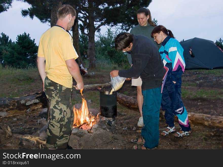 Hikers cook millet porridge on bonfire. Hikers cook millet porridge on bonfire