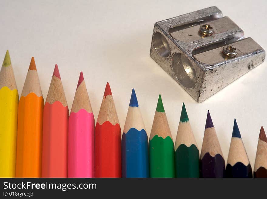 Coloured pencils with a pencil sharpener and pencil shavings. Coloured pencils with a pencil sharpener and pencil shavings.