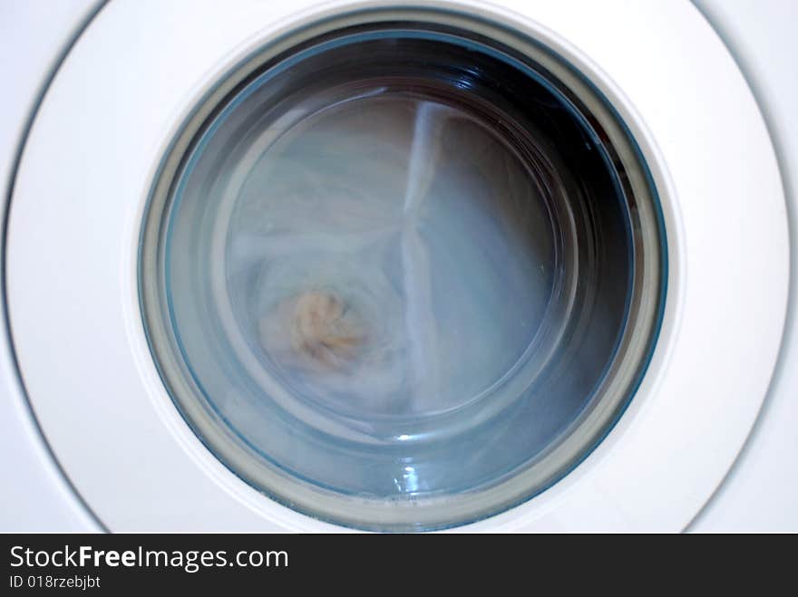 Close up of a washing machine. The drum is spinning and the contents blurred. Close up of a washing machine. The drum is spinning and the contents blurred