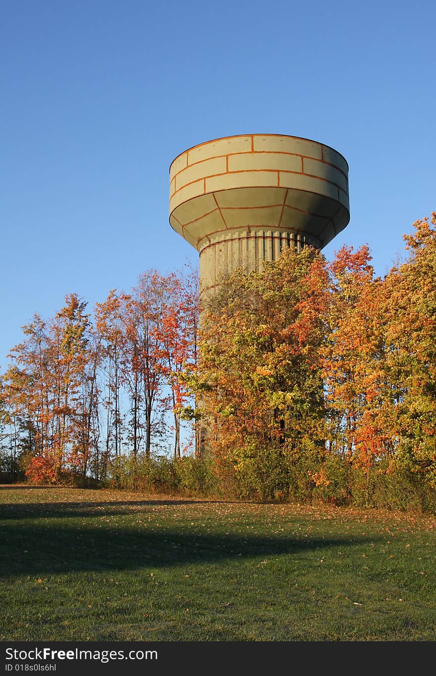 A water tower under construction behind bright autumn leaves