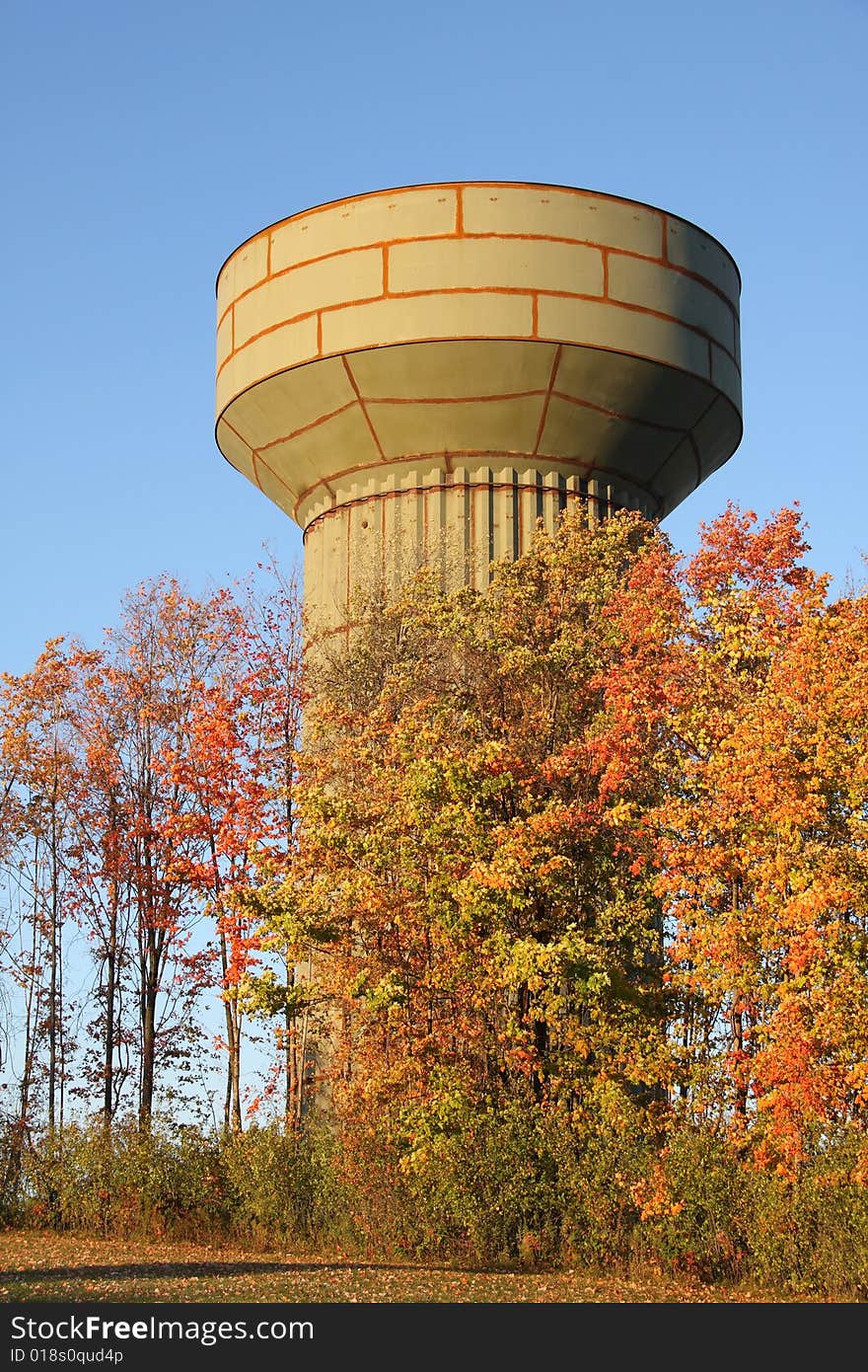 A water tower under construction behind bright autumn leaves