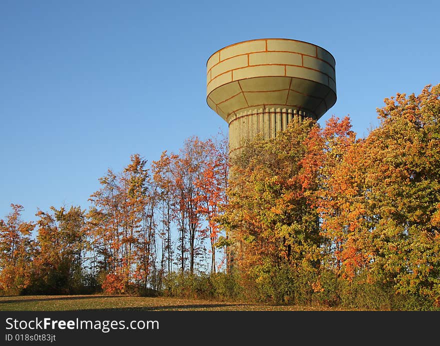 A water tower under construction behind bright autumn leaves