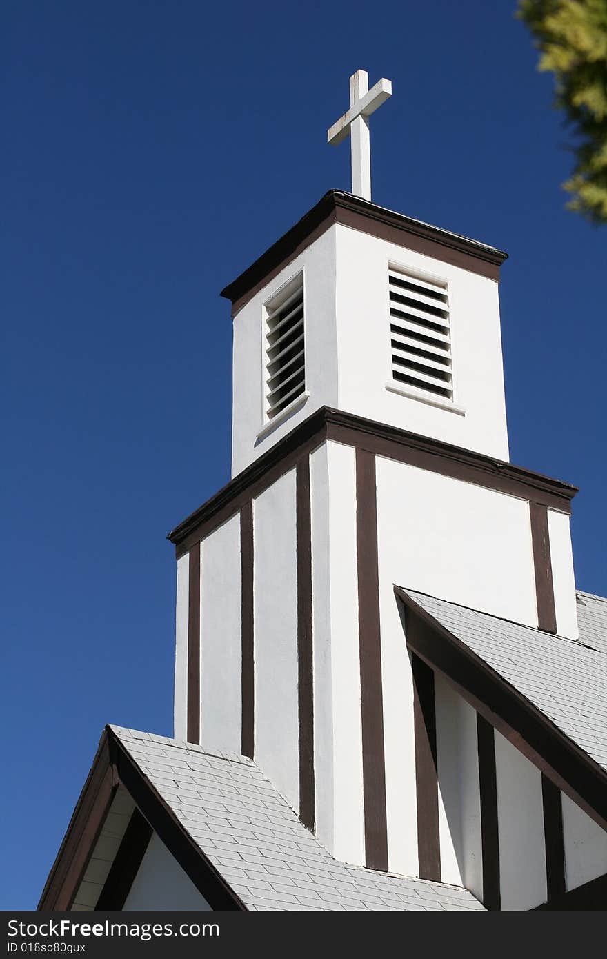 Old white church with cross on the blue sky background