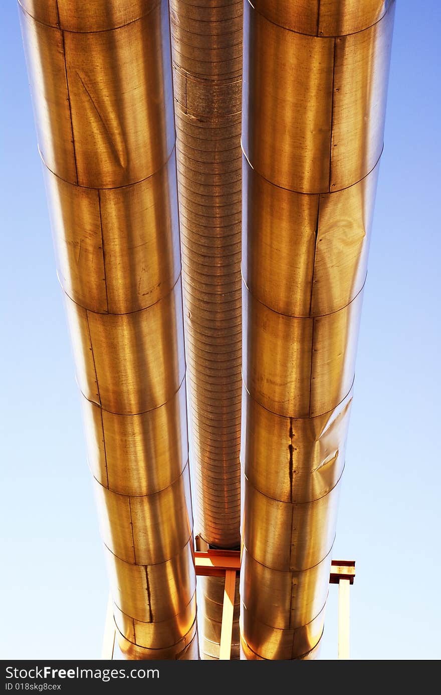 Industrial pipelines on pipe-bridge against blue sky