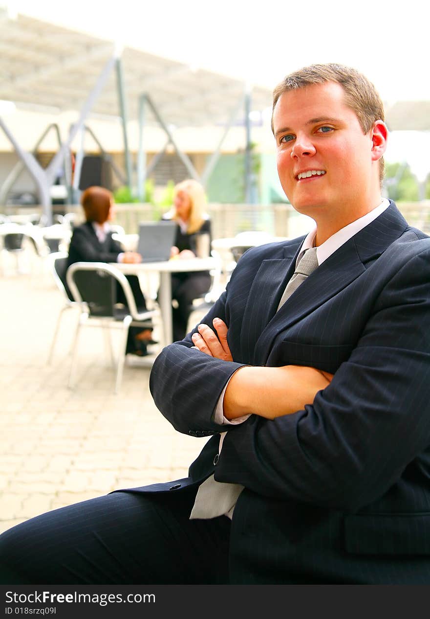 Successful business man hand folded and smiling with two of his associates on the background