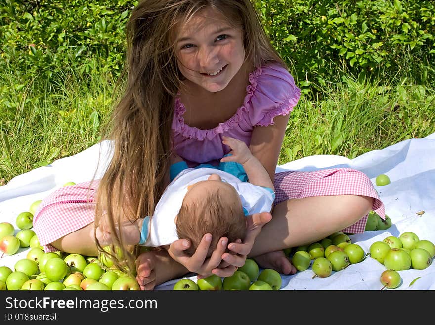 Little girl sitting with her baby brother among apples. Little girl sitting with her baby brother among apples